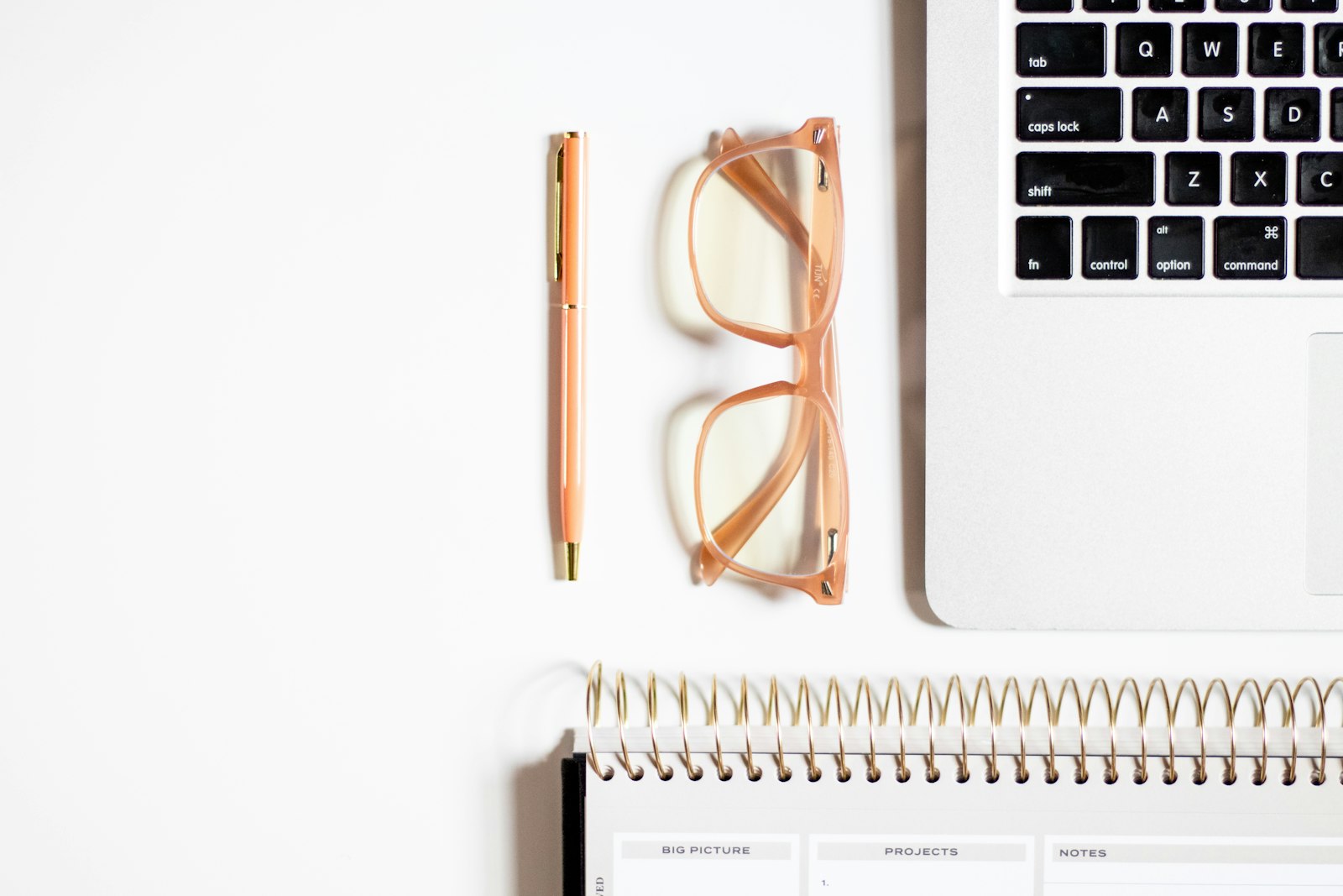 A desk with a notebook, glasses, and a laptop — the working end of a planning session
