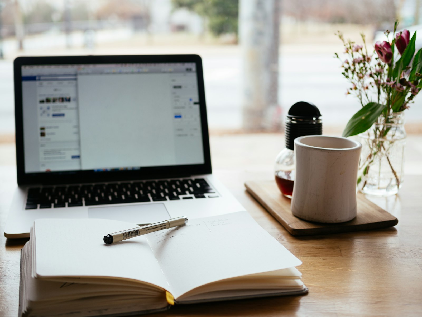 An open notebook and pen on a desk beside a laptop, set up for a study session