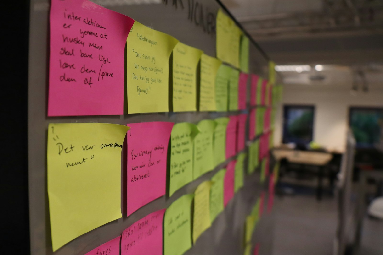 A wall covered in colourful sticky notes, arranged like an affinity diagram