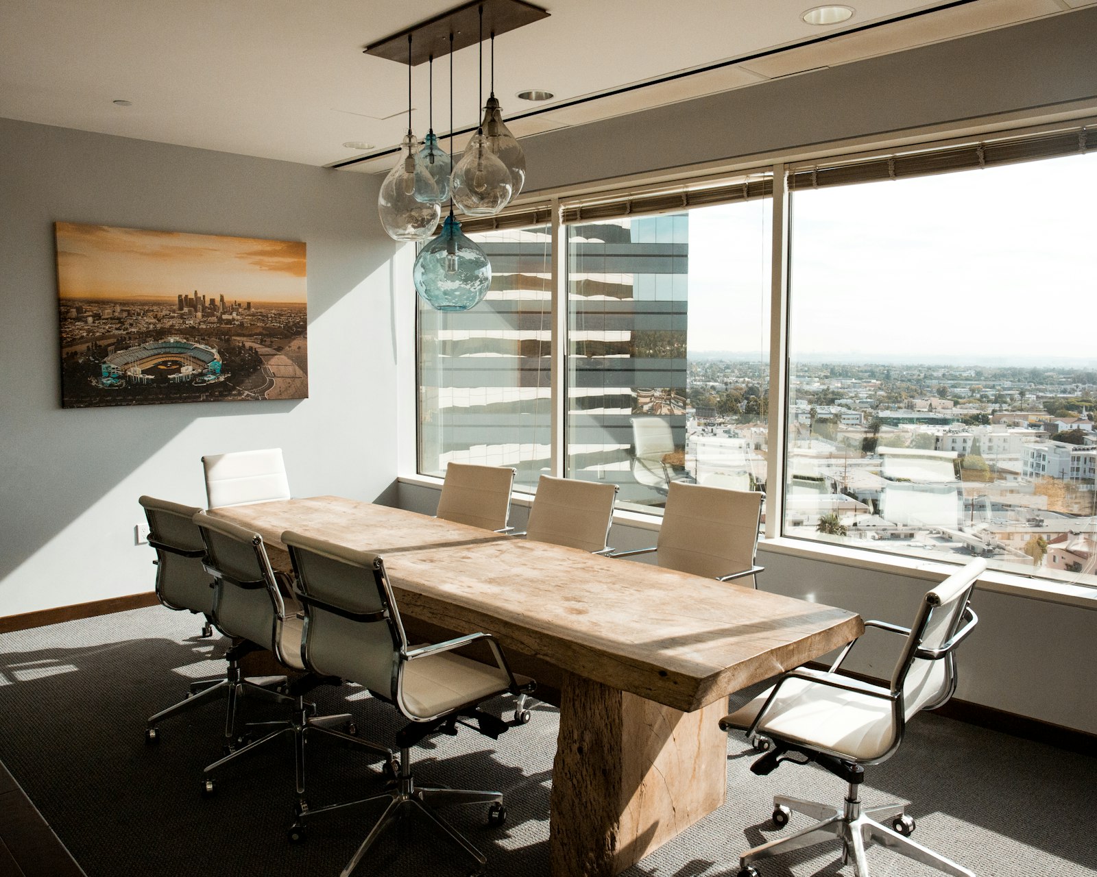 An empty boardroom table with a city skyline view through the window