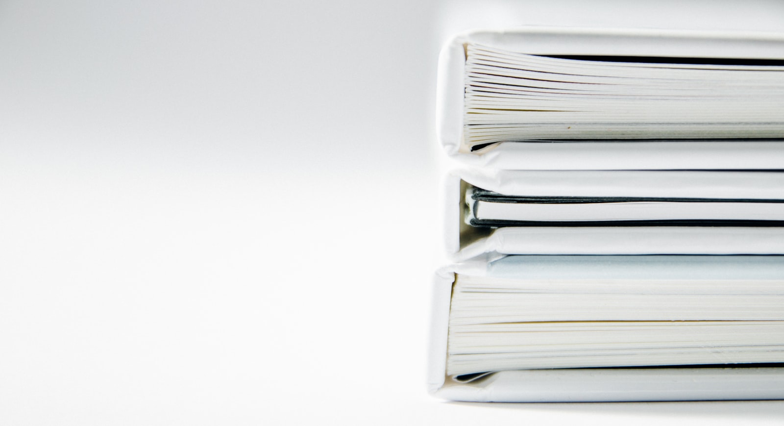 A stack of thick folders on a clean white surface